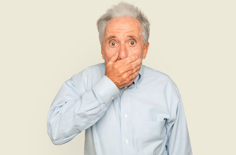 Shocked senior man with hand covering his mouth